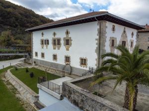 a building with a palm tree in front of it at Casa rural Iturrikoa in Urritzola