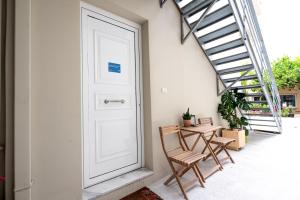 a porch with a white door and two chairs and a table at Serenity - Brand New Apt Near Athens Int Arpt in Spáta