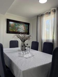 a dining room table with a white table cloth and a vase with flowers at Your Seaside Escape in Oropos in Skala Oropou