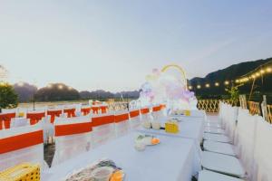 une table avec des tables blanches et des chaises orange sur le toit dans l'établissement Tam Coc Sky Bungalow, à Ninh Binh
