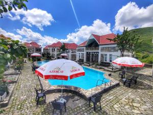 ein Resort mit einem Pool mit Sonnenschirmen in der Unterkunft FGarden Hotel Sheki in Şəki