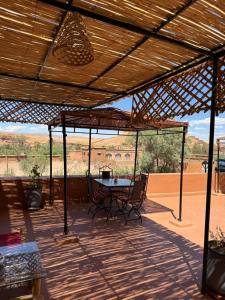 eine Terrasse mit einem Tisch und Stühlen unter einem Dach in der Unterkunft Auberge Ksar Ait Ben Haddou in Aït-Ben-Haddou