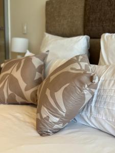 a bed with brown and white pillows on it at Cosy one bedroom apartment in Windhoek
