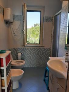 ein Bad mit einem WC, 2 Waschbecken und einem Fenster in der Unterkunft villa bella vista in Zambrone