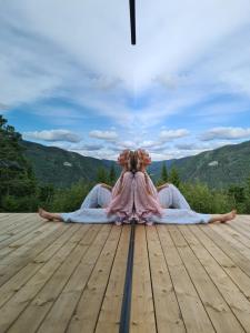 a woman in a dress sitting on a wooden deck at Vidsyn Midjås in Vistad