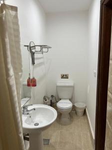 a white bathroom with a toilet and a sink at Lilly Rooms and Studio in Hurghada