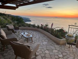 eine Terrasse mit Stühlen und Tischen und Blick auf das Meer in der Unterkunft villa bella vista in Zambrone