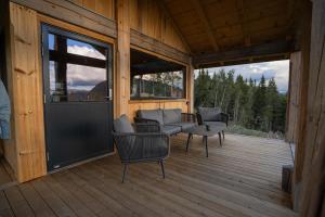 eine überdachte Veranda mit Stühlen und einer Couch auf einer Terrasse in der Unterkunft Vidsyn Midjås in Vistad