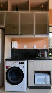 a kitchen with a washing machine and a microwave at Casa conforto e estilo in Palmas