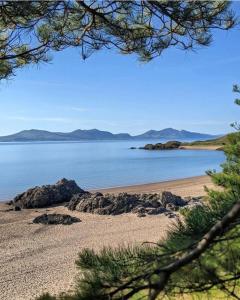 einen Strand mit Felsen und dem Ozean im Hintergrund in der Unterkunft Pen llyn holiday cottages and caravan in Newborough