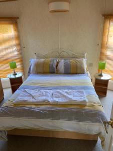 ein Schlafzimmer mit einem Bett mit zwei Lampen auf zwei Tischen in der Unterkunft Pen llyn holiday cottages and caravan in Newborough