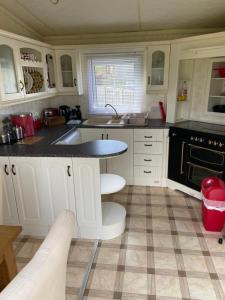 eine Küche mit weißen Schränken und einer schwarzen Arbeitsplatte in der Unterkunft Pen llyn holiday cottages and caravan in Newborough