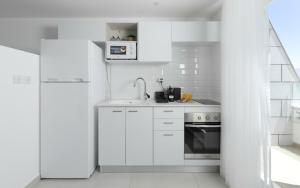 a white kitchen with a sink and a refrigerator at סוויטות עם נוף וצמודות לים במתחם SeaSide היוקרתי עם בריכה in Eilat