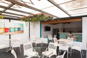 a dining room with white chairs and tables and a person at Almaviva Casa Hotel in Medellín