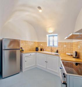a kitchen with white cabinets and a stainless steel refrigerator at Karpimo Scenery - Caldera Sunset View - Private Hot Tub - Firostefani in Firostefani
