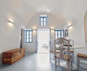Biały pokój ze stołem, krzesłami i drzwiami w obiekcie Karpimo Scenery w mieście Firostefani