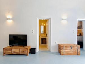 a living room with a flat screen tv and a coffee table at Karpimo Scenery - Caldera Sunset View - Private Hot Tub - Firostefani in Firostefani +42 photos