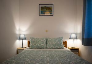 1 dormitorio con 1 cama con 2 lámparas en las mesas en ILIOCHARI sea view apartments Oropos - Kalamos en Kalamos