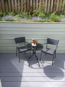 two chairs and a table with a vase of flowers on a patio at Rose's Cottage in Gorran Haven