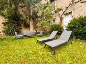Deux chaises et un banc dans l'herbe à côté d'un bâtiment dans l'établissement La maison de Jean-Pierre , à Devecey