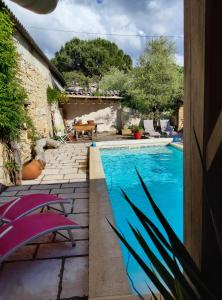 una piscina con sillas moradas junto a una casa en Chambre L'Orchidée en Vallon-Pont-dʼArc