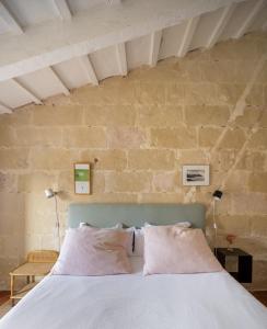 a bedroom with a white bed with a brick wall at Hotel Hevresac Singular & Small in Mahón