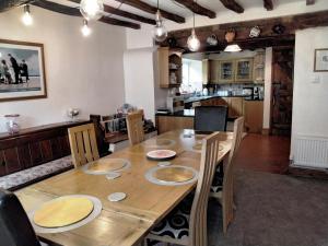 a dining room table with chairs and a kitchen at Cynynion Uchaf - Countryside Farmhouse with Views in Oswestry