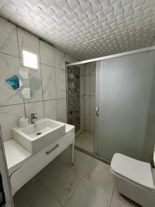 a white bathroom with a sink and a toilet at Erkal Pension in Antalya