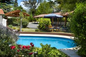 a swimming pool in a yard with a table and an umbrella at Posada Tantra in Villa General Belgrano +6 photos