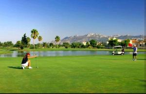 two people playing golf on a golf course with a lake at Casa Laya en Oliva Nova in Oliva
