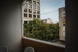 a window with a view of a tree and buildings at Pizana Budva Central in Budva +5 photos