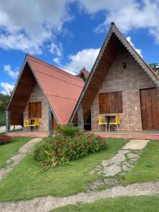dom z czerwonym dachem z krzesłami i kwiatami w obiekcie Chalés Flor do Caparaó em Patrimonio da Penha w mieście PatrimÃ´nio da Penha