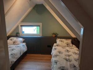 a attic room with two beds and a window at Vakantiehuis de Zonnehoed in Simpelveld