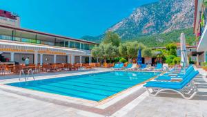 a swimming pool with blue lounge chairs and a mountain at Get Enjoy Hotels in Beldibi