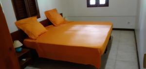 uma cama com almofadas laranja num quarto em Maison de 2 chambres avec terrasse amenagee et wifi a Gros Morne em Gros-Morne