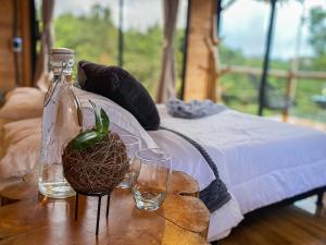 a table with two glasses and a bottle on a bed at Rùstico Glamping in Santa Elena