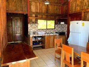 Una cocina con una mesa y un refrigerador blanco. en Entre Montañas, en Juayúa