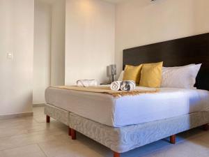 sypialnia z dużym łóżkiem z białą pościelą i żółtymi poduszkami w obiekcie Ceiba by Andiani w mieście Playa del Carmen