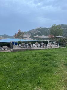 a patio with chairs and tables and a body of water at Hamre Apartments (Nicholas) in Agios Georgios Pagon