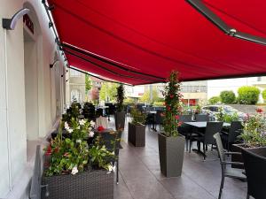 ザンクト・ガレンにあるNTN HOUSEのテーブルと椅子、赤い傘が備わるレストラン