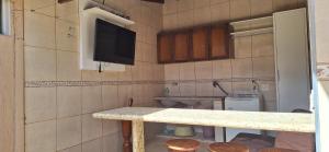 een kleine keuken met een aanrecht en een tv aan de muur bij Casa de Hospedagem Uberaba in Uberaba