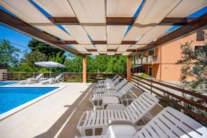 een rij witte ligstoelen naast een zwembad bij E-M Apartments with Private pool in Medulin