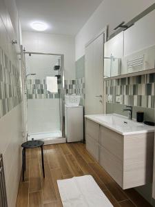 La salle de bains blanche est pourvue d'un lavabo et d'une douche. dans l'établissement Apartment Adriana, à Muggia