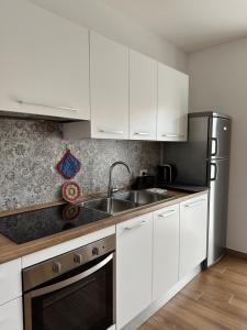 La cuisine est équipée de placards blancs et d'un réfrigérateur en acier inoxydable. dans l'établissement Apartment Adriana, à Muggia