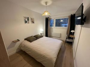 - une chambre avec un lit blanc et une fenêtre dans l'établissement Grand appartement lumineux au cœur de Thonon, à Thonon-les-Bains