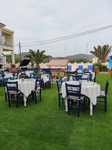 un grupo de mesas y sillas sentados en el césped en Oceanida Bay Hotel en Pythagoreio