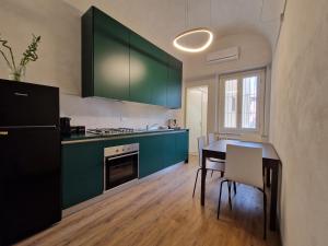 une cuisine avec des armoires vertes, une table et des chaises dans l'établissement Lo Strullo, à Pise