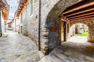 Une allée dans un ancien bâtiment en pierre avec une arche dans l'établissement Rifugio Escursionistico La Ruà, à Macra