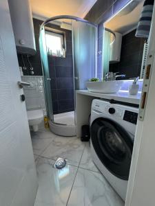 a bathroom with a washing machine and a sink at Apartman Alchemist I in Bosanska Dubica