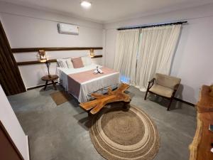 a bedroom with a large bed and a table at Pousada Ventos da Barra in Barra de Santo Antônio